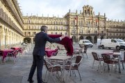 Un  trabajador extiende el mantel en la mesa de una terraza de la la plaza Mayor de Salamanca. ICAL