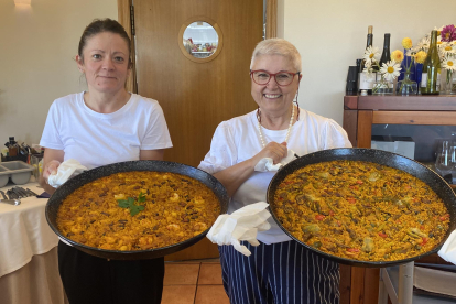 Eva Munera y Laura Fernández con dos paellas antes de servir a la mesa en el restaurante Villa Mencía en Corullón.  /