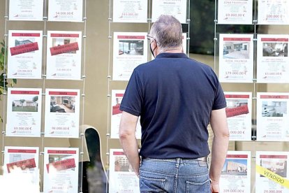 Un vecino observa las ofertas de pisos en venta y alquiler en una inmobiliaria de Valladolid. ICAL