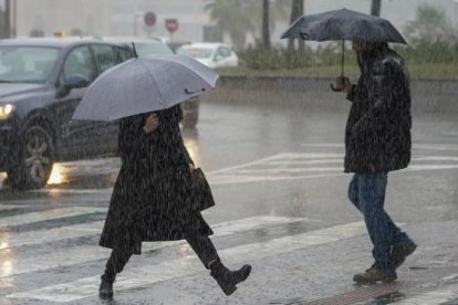 Transeúntes pasean bajo la lluvia en una imagen de archivo
