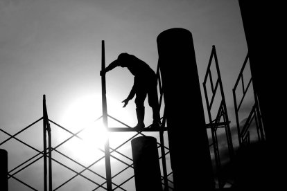 Un operario de la construcción trabaja subido a un andamio.