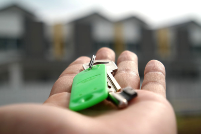 Un joven muestra la llave de su vivienda frente a una promoción de adosados. PQS / CCO