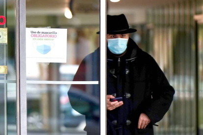 Un usuario sale de un centro de salud de Valladolid con la mascarilla puesta, junto a un cartel que recuerda su uso obligatorio. PHOTOGENIC