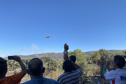 Los vecinos observan uno de los aviones que trabaja en la extinción del incendio de Navalacruz.- ICAL