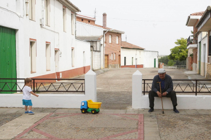 Un pequeño juega junto a una persona mayor en la localidad vallisoletana de Mayorga.- ICAL