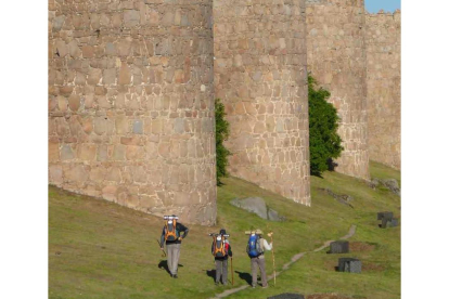 Peregrinos transitan por el camino que discurre paralelo a la Muralla de Ávila.- ÁVILA TURISMO