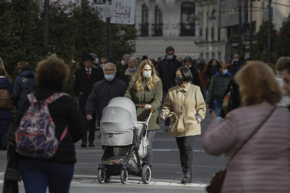 Una joven pasea por las calles del centro de Valladolid con el recién nacido en el capazo. J.M. LOSTAU