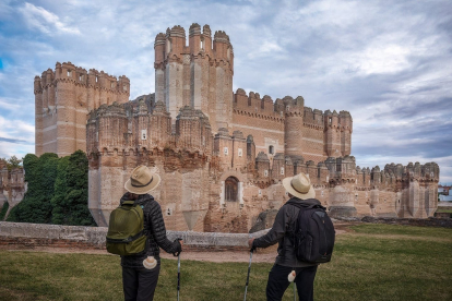 Dos peregrinos contemplan el castillo de la localidad segoviana de Coca.- PRODESTUR SEGOVIA