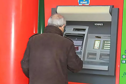 Una persona mayor utiliza un cajero automático en el exterior de una sucursal bancaria. EUROPA. PRESS