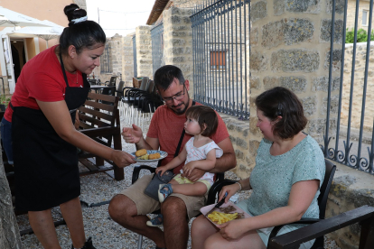 Aurora Benítez ofrece unas croquetas a la hija de unos clientes del bar de Villalaco, Palencia.- ICAL