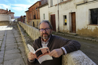 El escritor Vicente Fernández-Merino posa con su libro en las calles de Fuentes de Valdepero. MANUEL BRÁGIMO