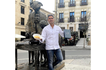 Gonzalo Sendín, en la escultura que recuerda a Churriguera, con las cajas para llevar. A su espalda, el mesón familiar. - ARGICOMUNICACIÓN