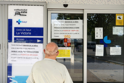 Un señor mira los carteles indicativos en la entrada de un centro de salud del barrio de La Victoria, en Valladolid. - ICAL