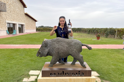 Lucía San José, frente a la escultura realizada por Ricardo Flecha, con una botella de su vino Madremía.