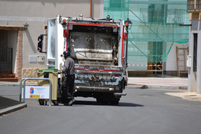 Un operario mueve un contenedor junto al camión de la basura. - D. M.