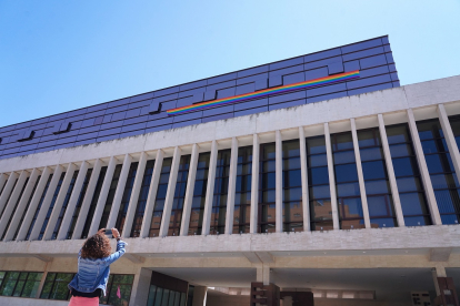 Una mujer fotografía la bandera arcoiris colocada en la sede de las Cortes.- ICAL