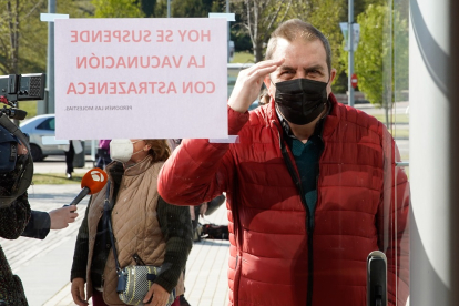Un ciudadano se asoma a las puertas del Centro Cultural Miguel Delibes, junto a un cartel que anuncia la suspensión de la vacunación con AstraZeneca.- J. M. LOSTAU