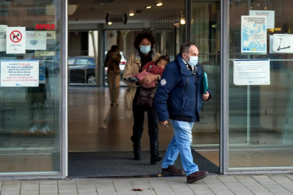 Usuarios salen de un centro de salud de Valladolid con la mascarilla puesta, junto a carteles que recuerdan su uso obligatorio. PHOTOGENIC