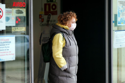 Una usuaria sale de un centro de salud de Valladolid con la mascarilla puesta, junto a carteles que recuerdan su uso obligatorio. PHOTOGENIC