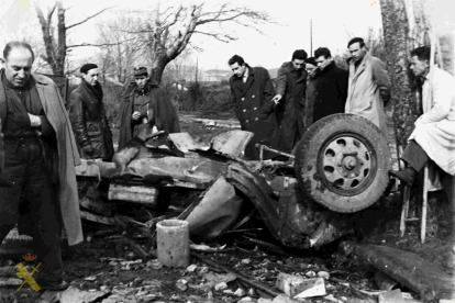 Accidente con vuelco de vehículo en el que se aprecia al teniente de la Guardia Civil y varios civiles observando el mismo. 1956