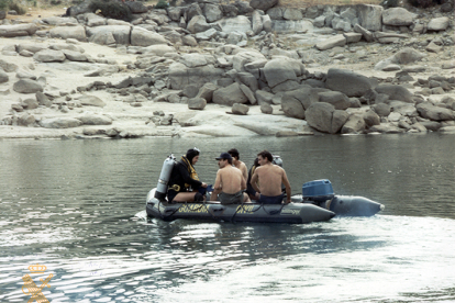 Cinco componentes del GEAS de la 1ª Zona, en una lancha neumática, dos de ellos con el equipo de buceo completo preparados para sumergirse en el agua. 1985