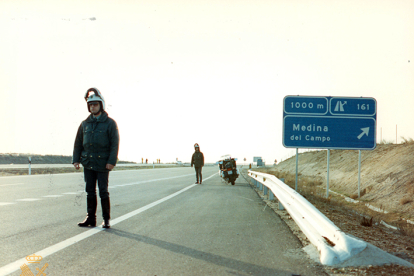 Motoristas a pie de carretera en autovía junto a cartel indicador de salida. 1995