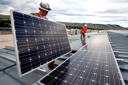 Dos operarios instalan paneles solares en el tejado de una edificación. PQS / CCO