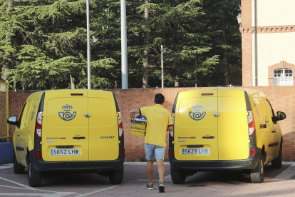 Un repartidor de Correos, en Palencia, se dispone a cargar una caja con cartas en un vehículo.