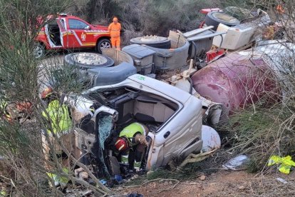 Los bomberos trabajan para excarcelar al conductor en el camión volcado en León