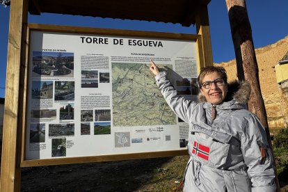 Inma Gómez señala el panel informativo de las rutas de senderismo habilitadas en Torre de Esgueva.