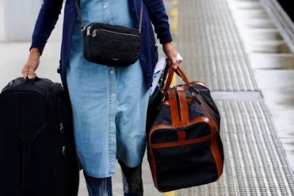 Una persona carga con maletas en una estación de ferrocarril.