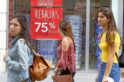 Varias personas pasan por delante de una tienda del centro de Valladolid.