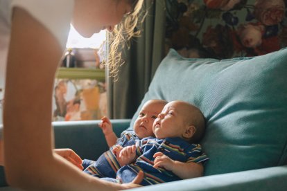 Una madre cuida a sus bebés gemelos en casa, una escena cotidiana que ilustra la realidad de las familias con partos múltiples