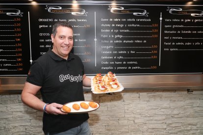 Alejandro Burgos muestra un plato con croquetas de huevo cocido y una bandeja con varias tapas de queso de cabra, mermelada y cebolla caramelizada.