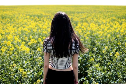 Una mujer observa un cultivo de colza