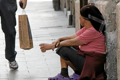 UNA PAREJA PASA JUNTO A UN POBRE QUE PIDE LIMOSNA CERCA DEL AYUNTAMIENTO DE VALLADOLID, EN LA IGLESÍA DE JESÚS NAZARENO. MENDICIDAD. POBREZA. HORIZONTAL