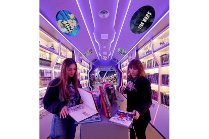 Dos personas consultan dos cómics en una tienda especializada.