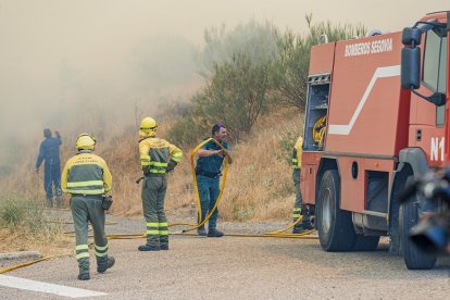 Efectivos de los bomberos de Segovia, de la Junta de Castilla y León y Protección Civil trabajan en la extinción del incendio en la Nacional-110.- ICAL