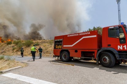 Efectivos de los bomberos de Segovia, de la Junta de Castilla y León y Protección Civil trabajan en la extinción del incendio en la Nacional-110.- ICAL