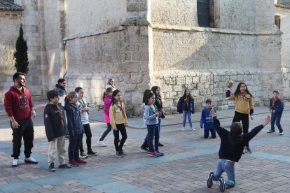 Algunos de los integrantes del Grupo Scout San Miguel de Palencia juegan a la vaca sentada en la plaza de San Miguel.-ICAL