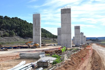 Dos operarios clasifican ferralla al pie de los soportes del viaducto, junto a Valbuena - S. G. C.