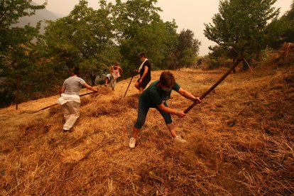 Vecinos de Lusio (León), realizan desbroces alrededor del pueblo ante la posible llegada del incendio.