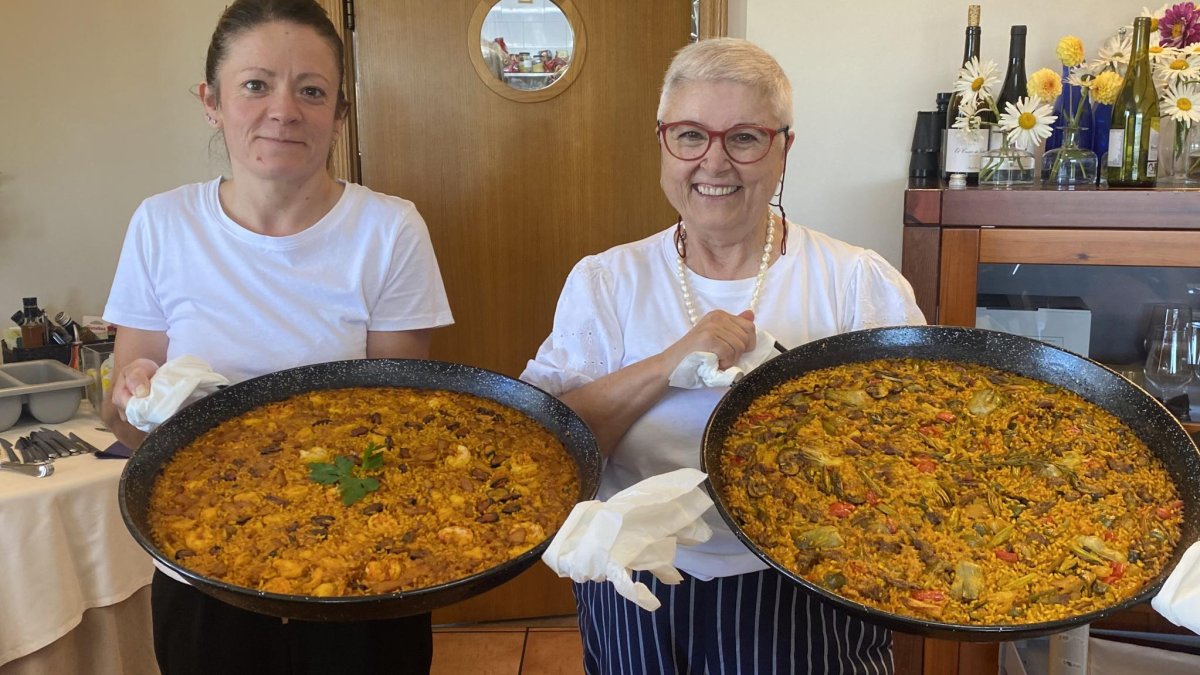 Eva Munera y Laura Fernández con dos paellas antes de servir a la mesa en el restaurante Villa Mencía en Corullón.  /