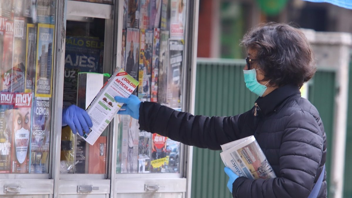 Una mujer compra la prensa durante el Estado de alarma por el coronavirus. - ICAL