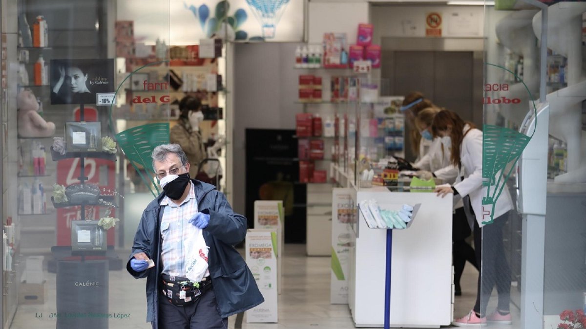 Un hombre protegido con mascarilla y guantes sale de una Farmacia. En Madrid (España) a 14 de abril de 2020. - Europa Press