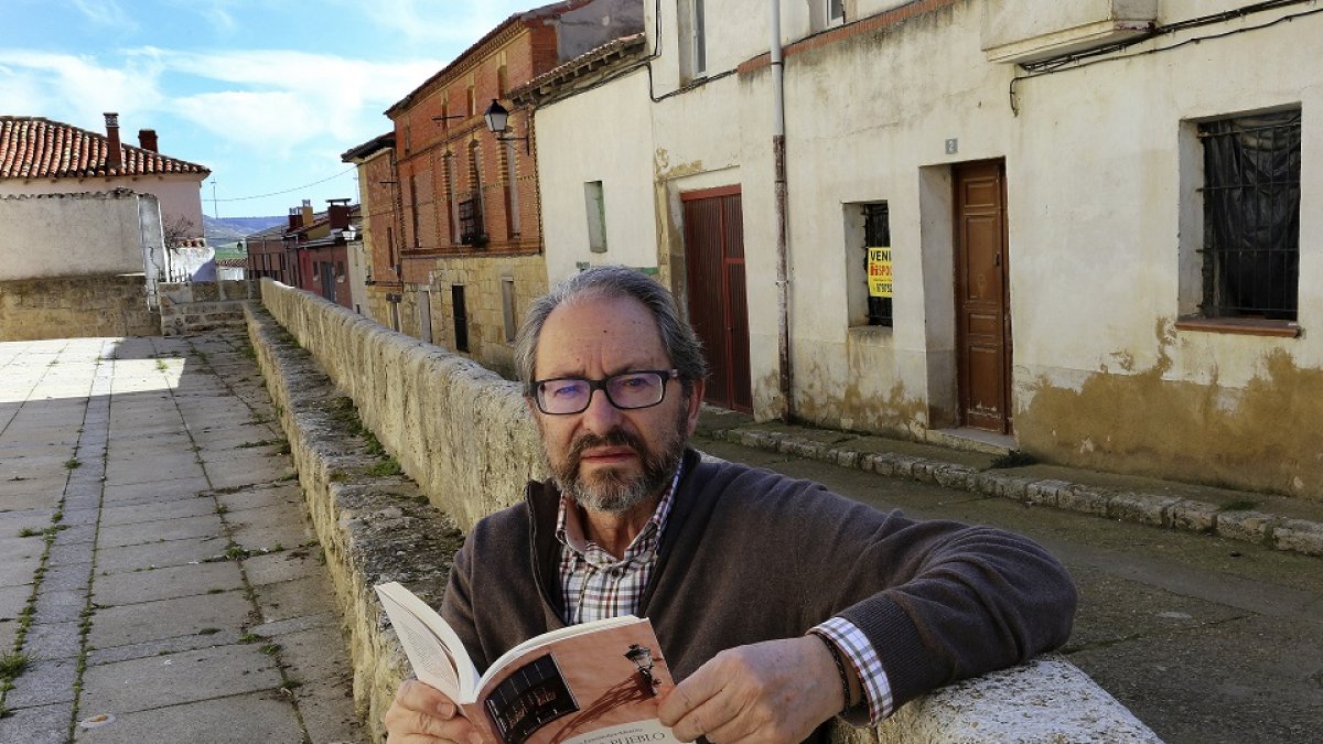 El escritor Vicente Fernández-Merino posa con su libro en las calles de Fuentes de Valdepero. MANUEL BRÁGIMO