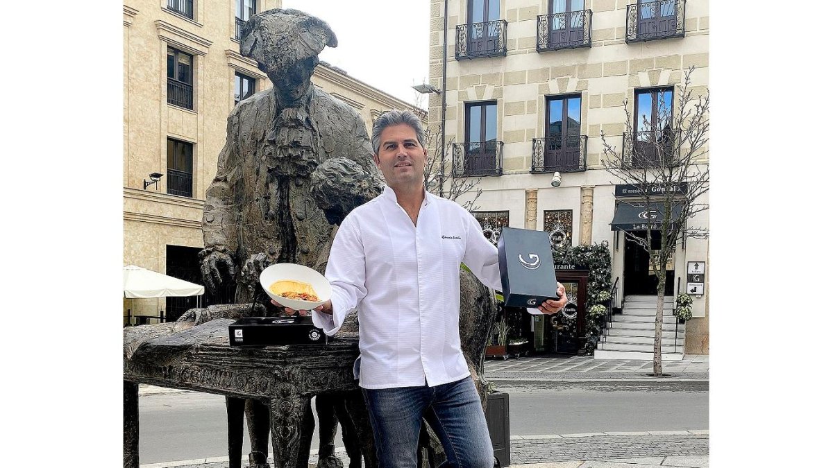 Gonzalo Sendín, en la escultura que recuerda a Churriguera, con las cajas para llevar. A su espalda, el mesón familiar. - ARGICOMUNICACIÓN