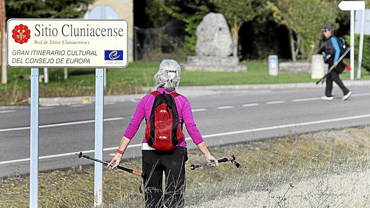 Una peregrina mira un cartel identificativo del Camino de Santiago en Carrión de los Condes (Palencia).- ICAL