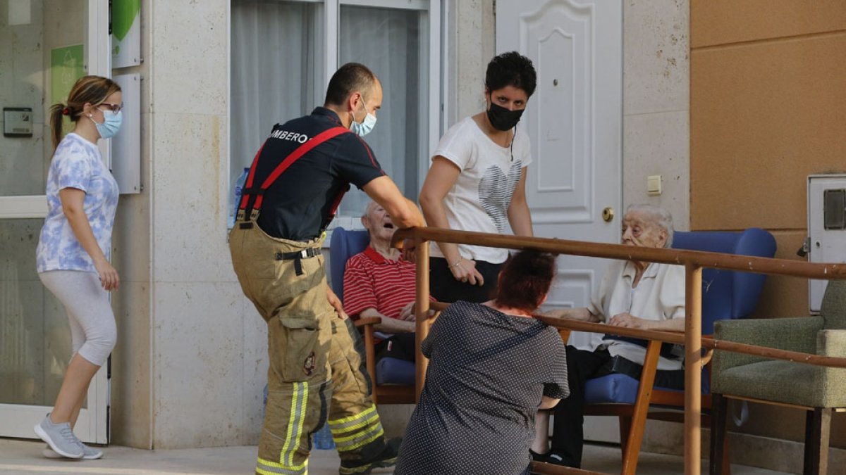 Un operario del cuerpo de Bomberos de Burgos en la residencia siniestrada, junto a residentes y empleados. SANTI OTERO