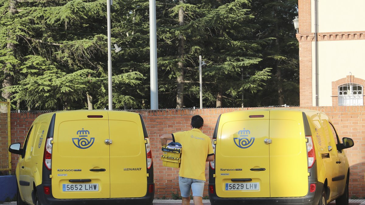 Un repartidor de Correos, en Palencia, se dispone a cargar una caja con cartas en un vehículo.